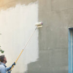 house painter painting building exterior with roller